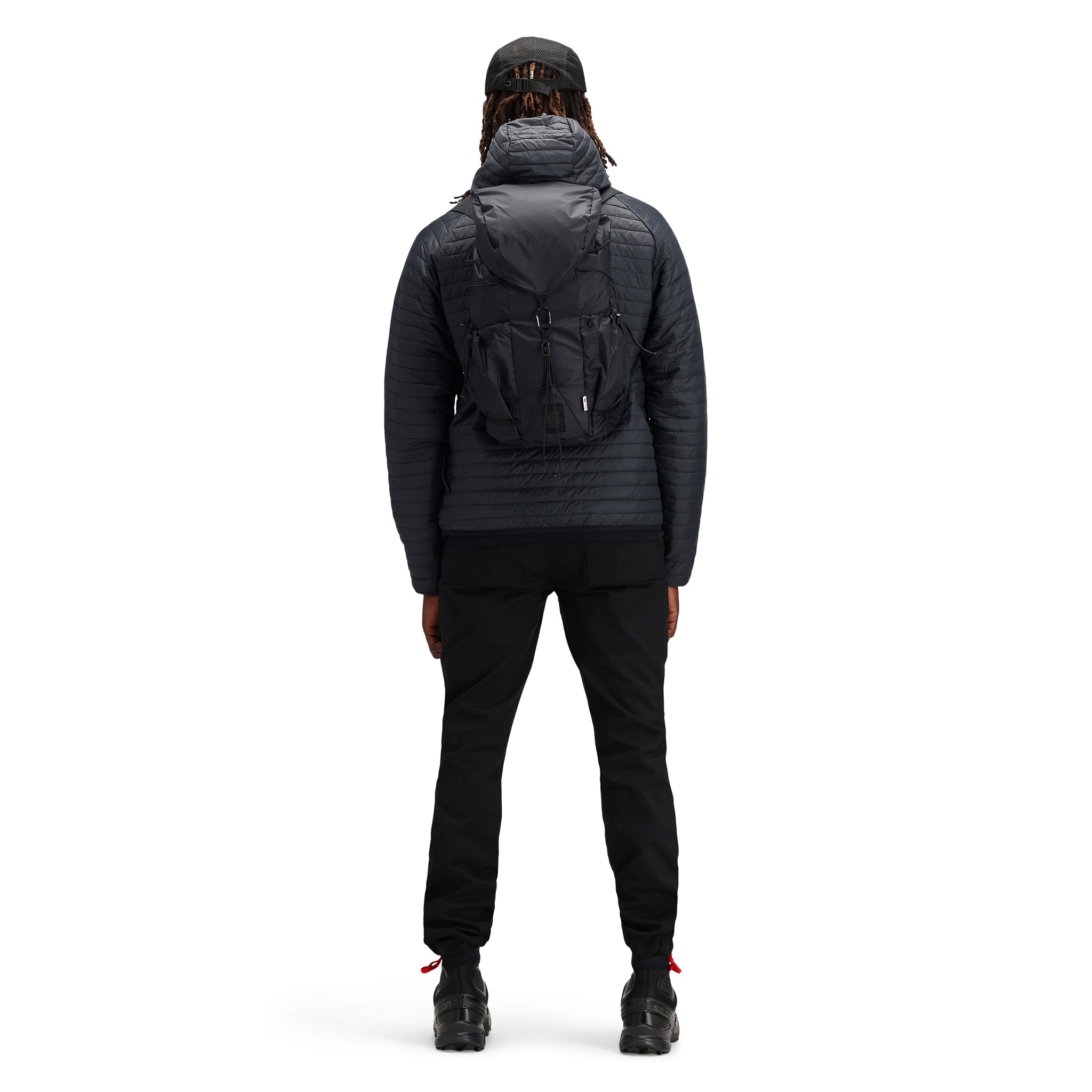 Model wearing Topo Designs TopoLite Cinch Pack 16L packable daypack backpack for travel in "black"