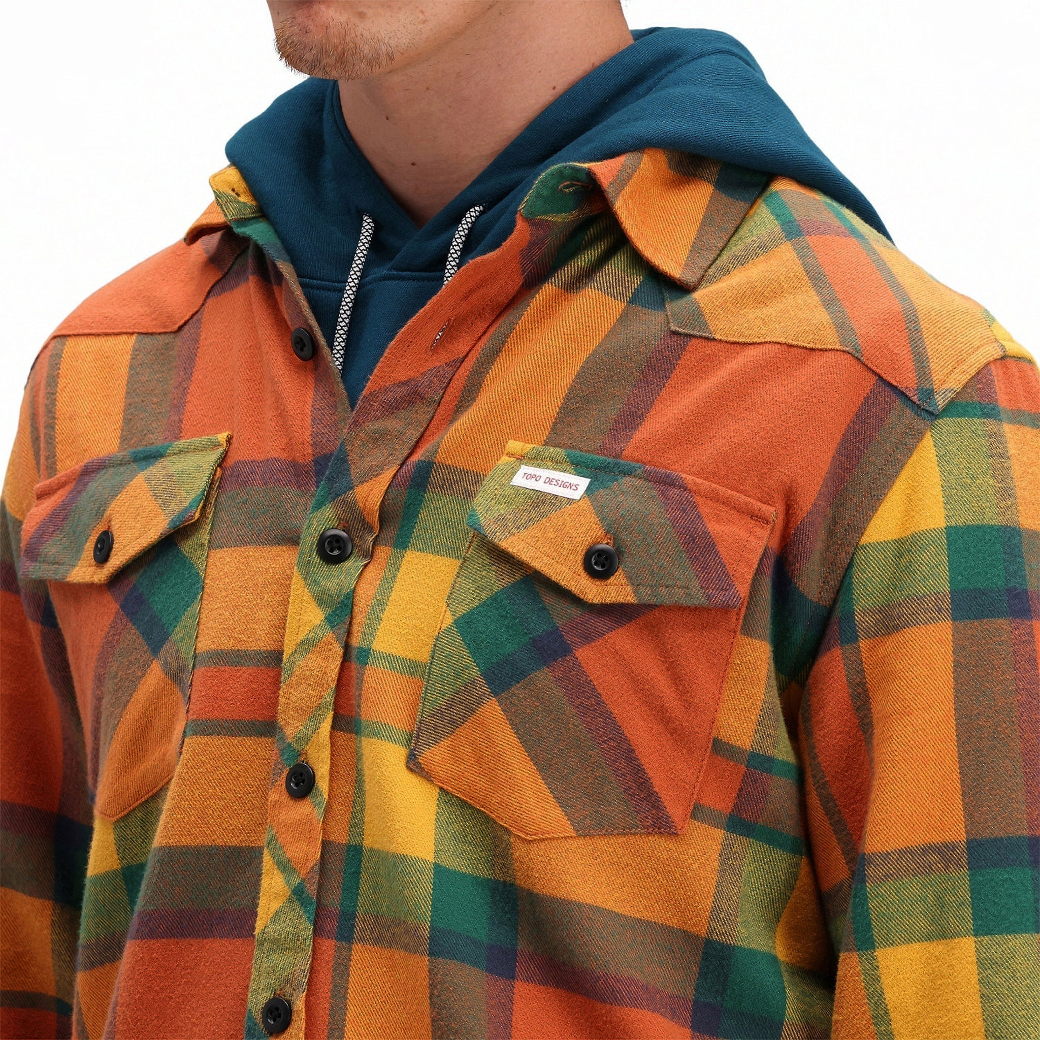 Front model shot of Topo Designs men's mountain organic cotton flannel shirt in "brick / mustard plaid" orange