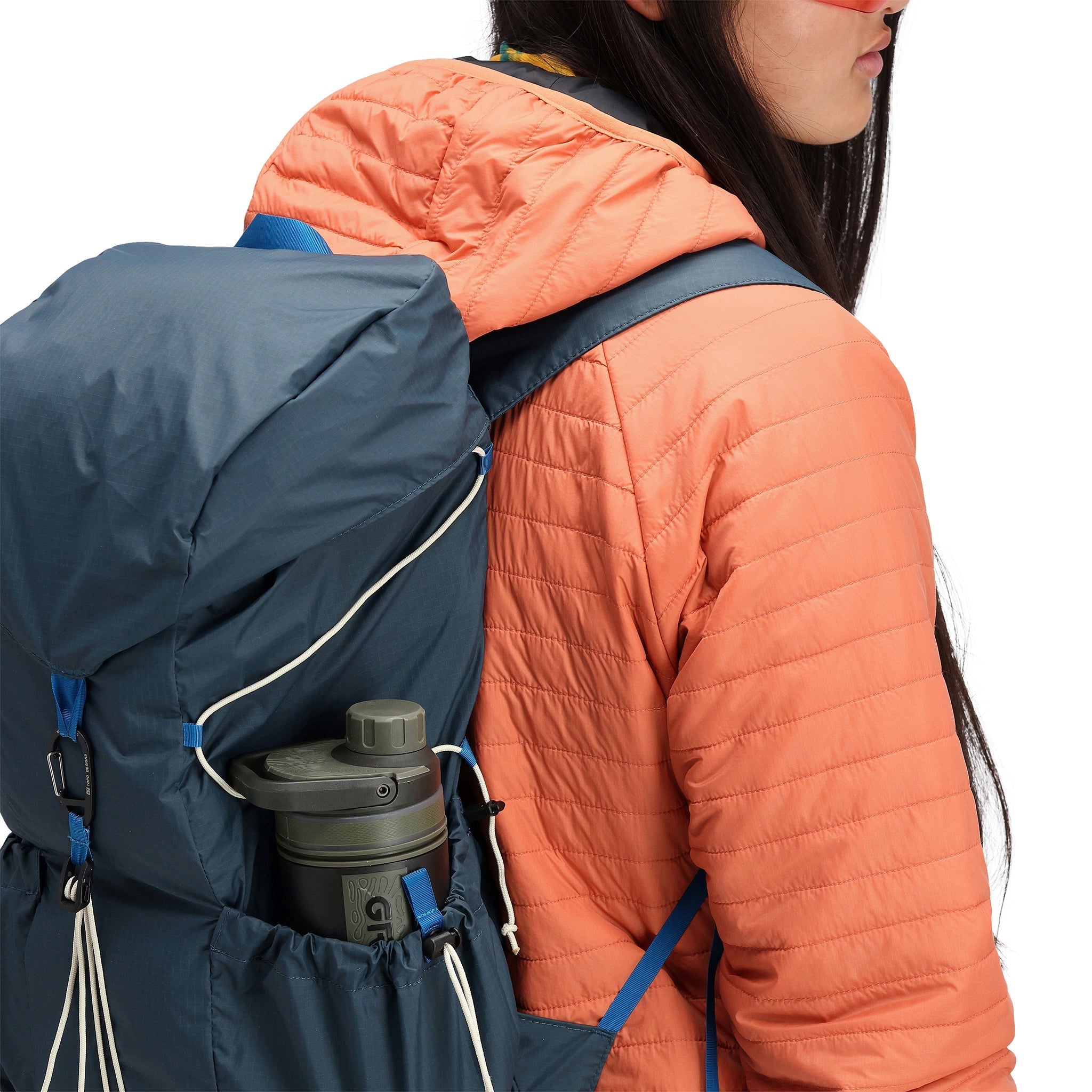 Model wearing Topo Designs TopoLite Cinch Pack 16L packable daypack backpack for travel in "pond blue"