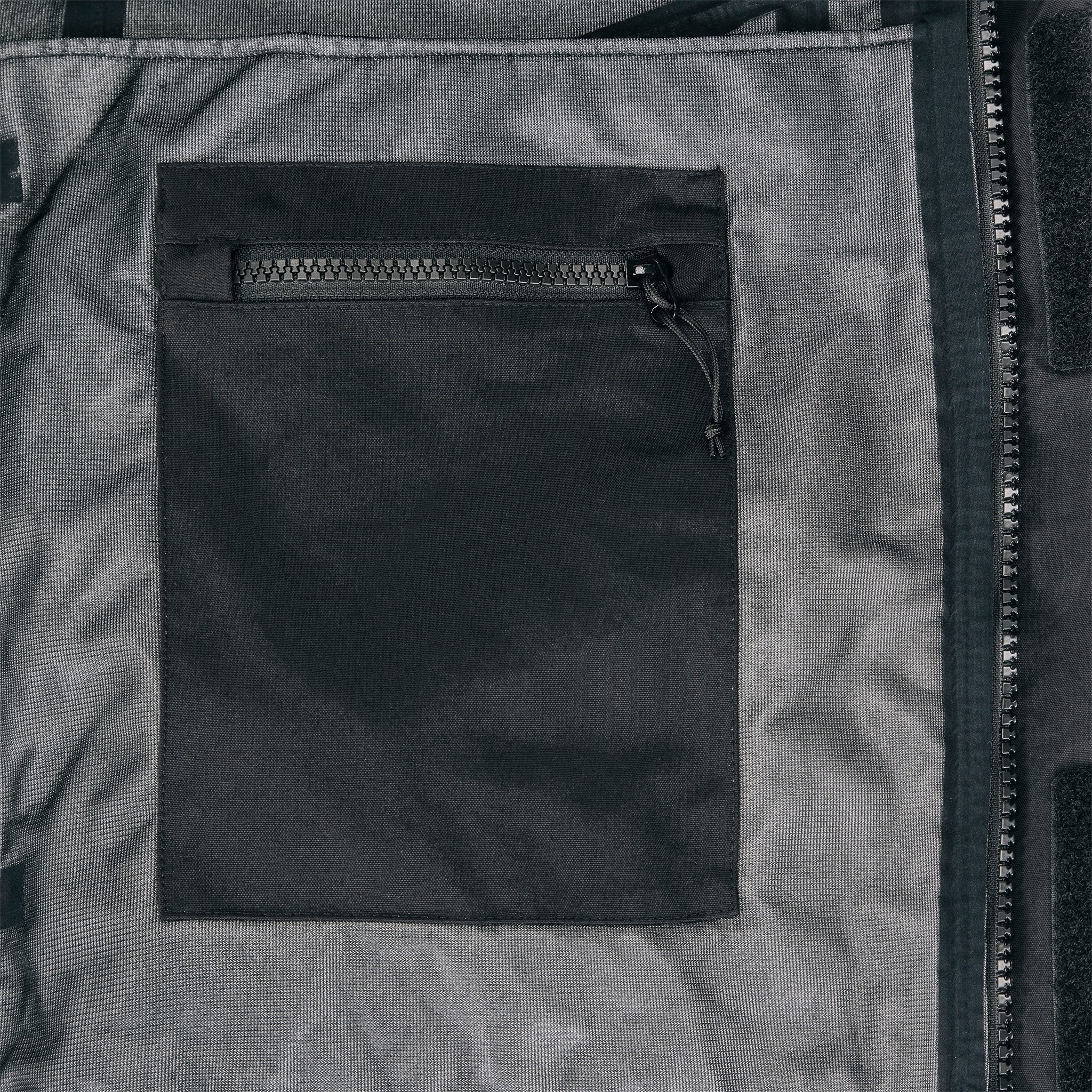 General shot of internal chest zipper pocket on Topo Designs Men's Mountain Parka waterproof shell jacket in black.