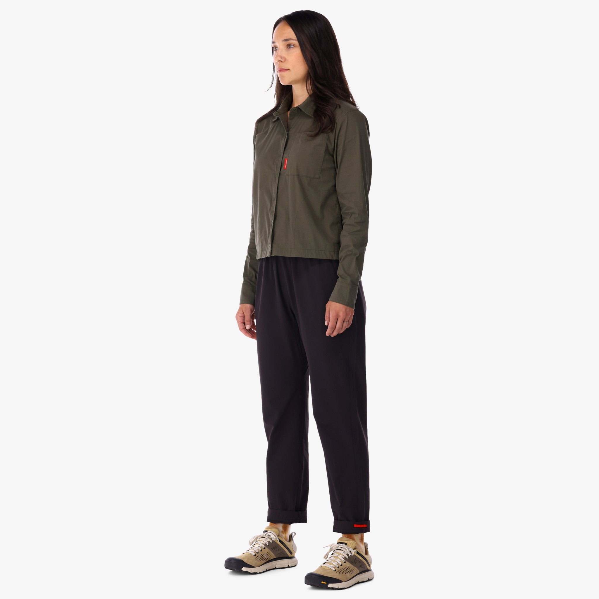 Side model shot of Topo Designs Women's Global long sleeve lightweight snap travel shirt in "olive" green on model front.