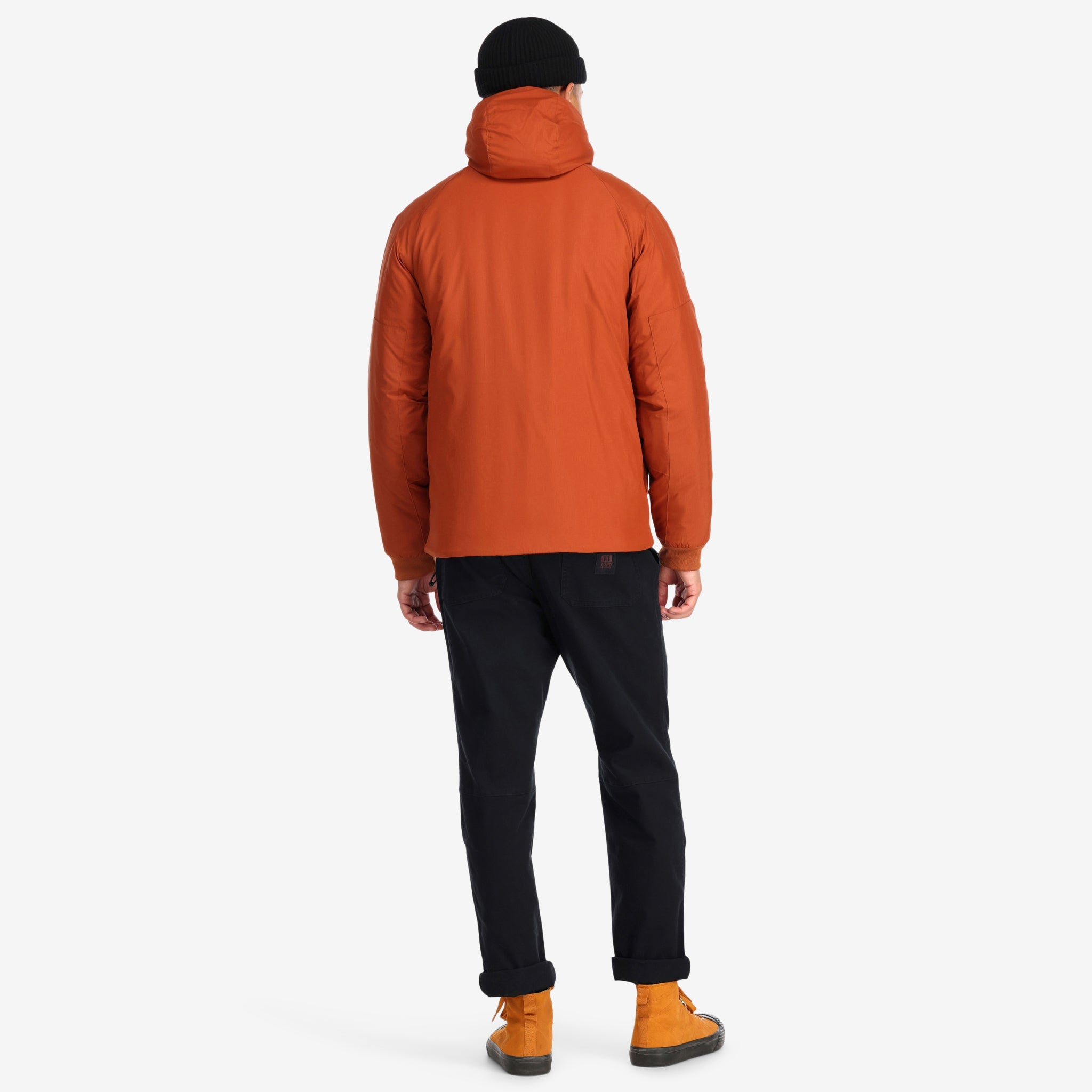 Back model shot of Topo Designs Mountain Puffer Primaloft insulated Hoodie jacket in "Brick" orange