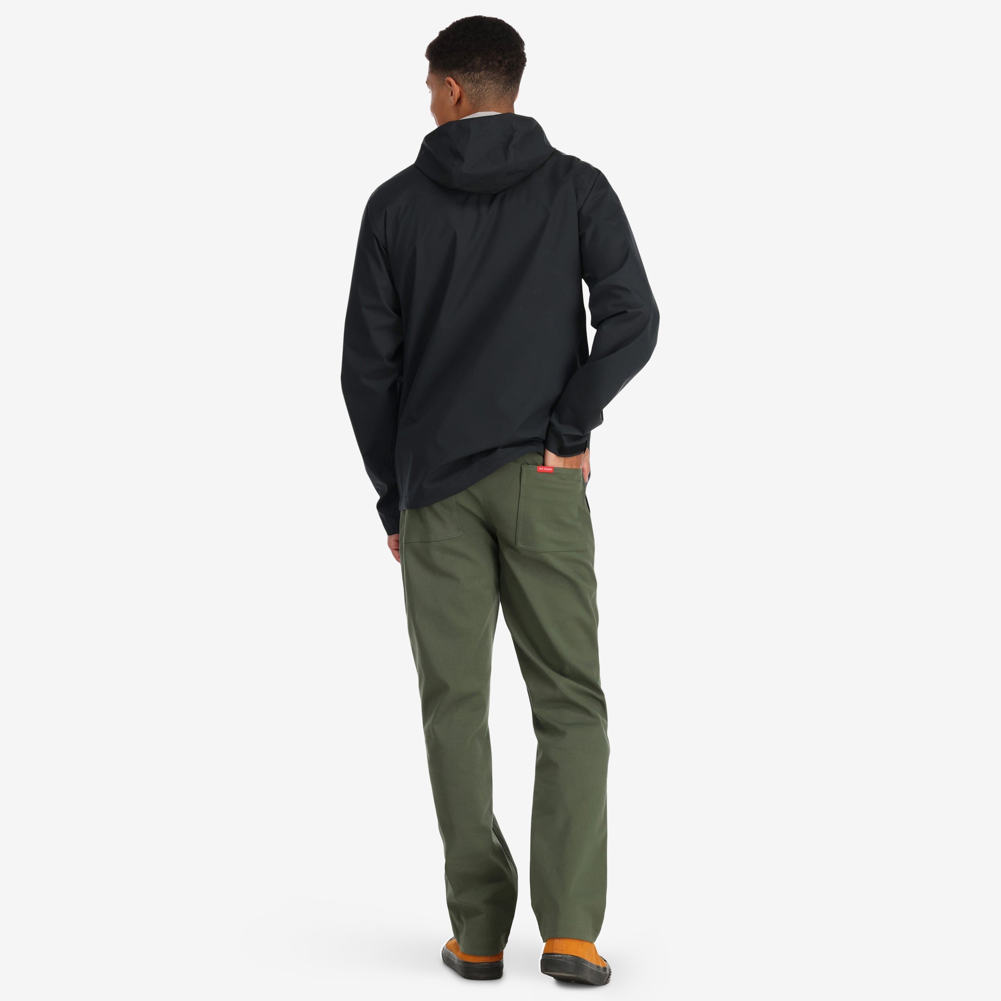 Back of model wearing Topo Designs Men's Global Pants lightweight cotton nylon travel pants in olive green.