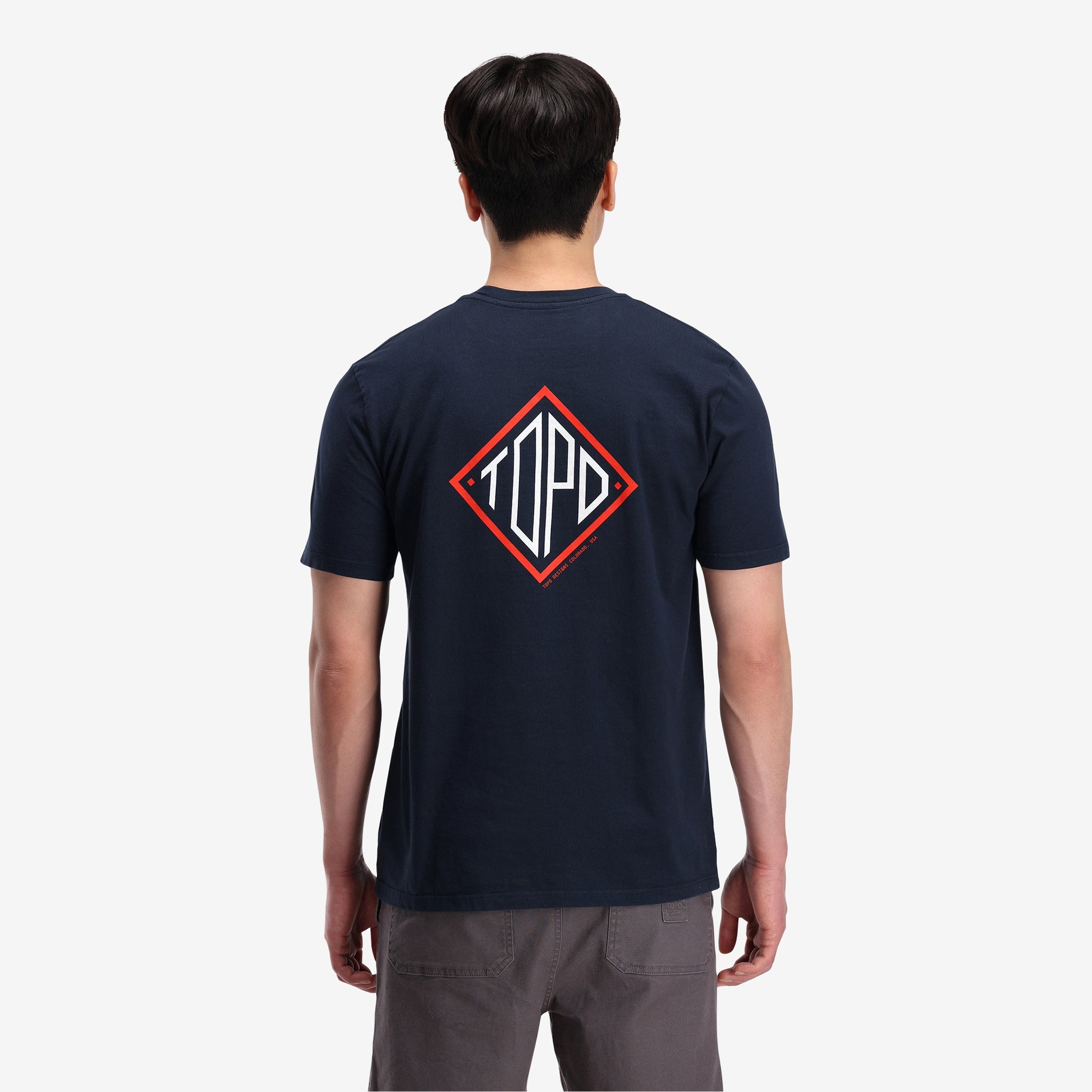 General shot, on model back view of Topo Designs Men's Small Diamond Tee 100% organic cotton short sleeve graphic logo t-shirt in "navy" blue.